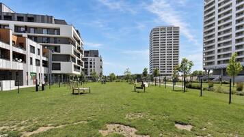A grassy area with benches, surrounded by modern apartment buildings.
