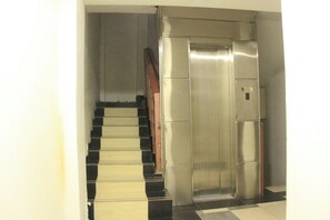 A staircase leading to a metallic elevator. -  Exclusive Studios in Nairobi-kitchenette, WiFi, TV, fridge, microwave and more. (Nairobi)