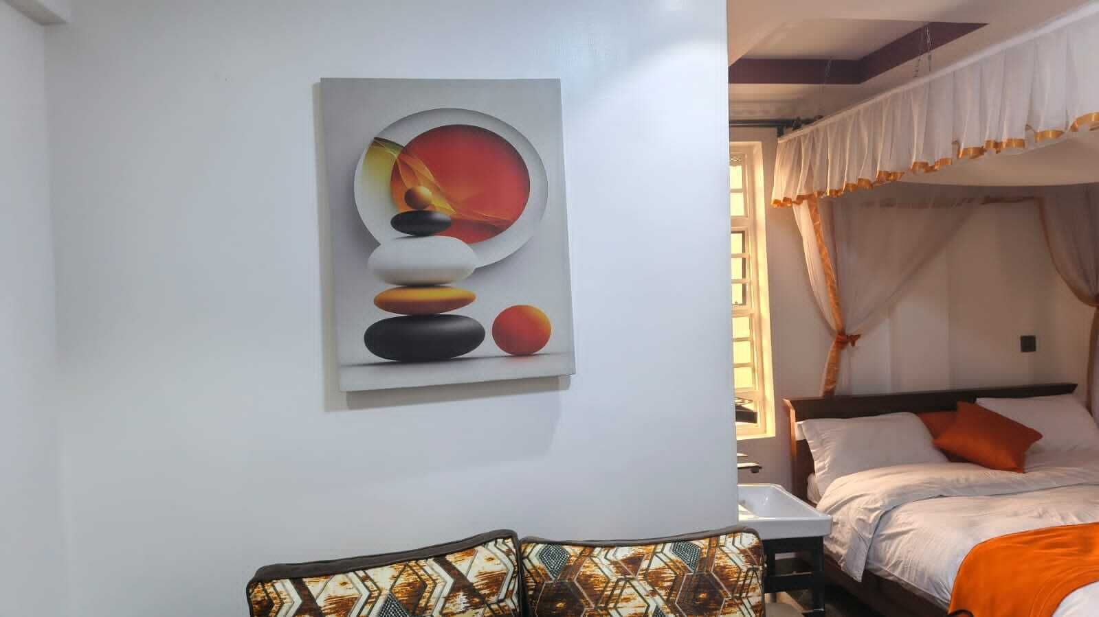 Ein Schlafzimmer mit Bett, Nachttisch, Wandbild und Fenster mit Vorhängen.