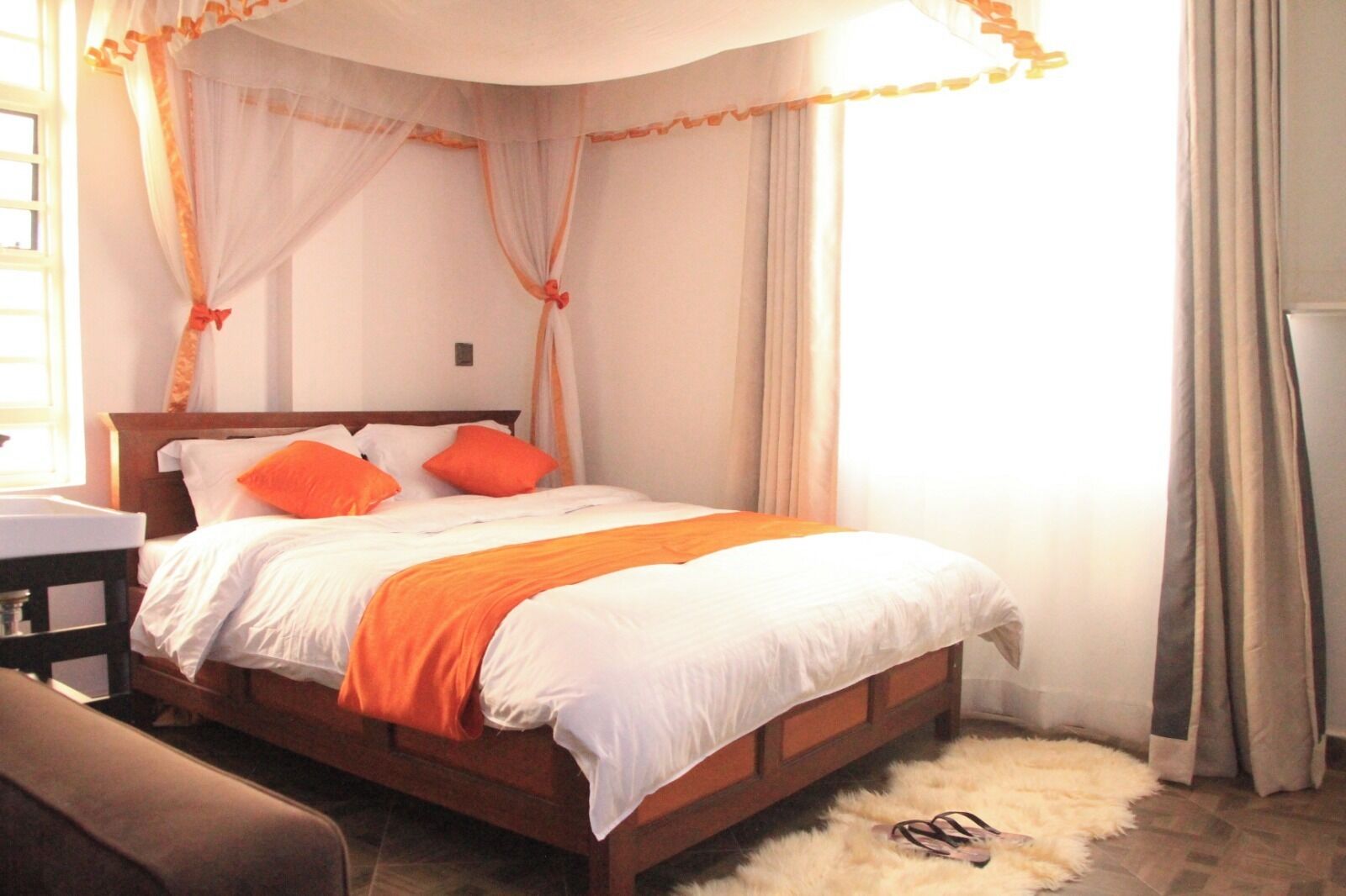 A bed with a canopy, a chair, a small table, and a fluffy rug.