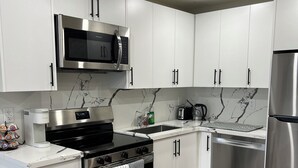 A modern kitchen with white cabinets, stainless steel appliances, a black stove, and a wooden floor. - Modern Lakeview Stay Near Downtown Huntsville (Huntsville)