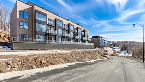 A modern multi-story building with balconies, a flat roof, and a paved road in front. - Modern Lakeview Stay Near Downtown Huntsville (Huntsville)