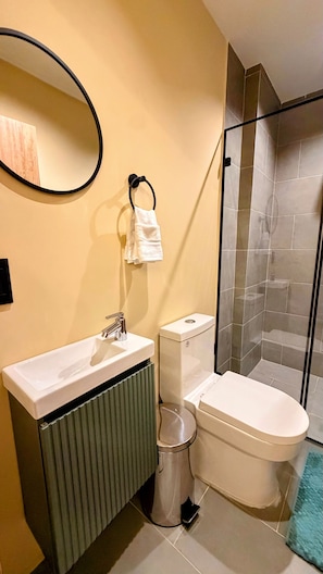 A bathroom with a toilet, sink, and a shower area. - Nam Hotel Boutique (Medellín)