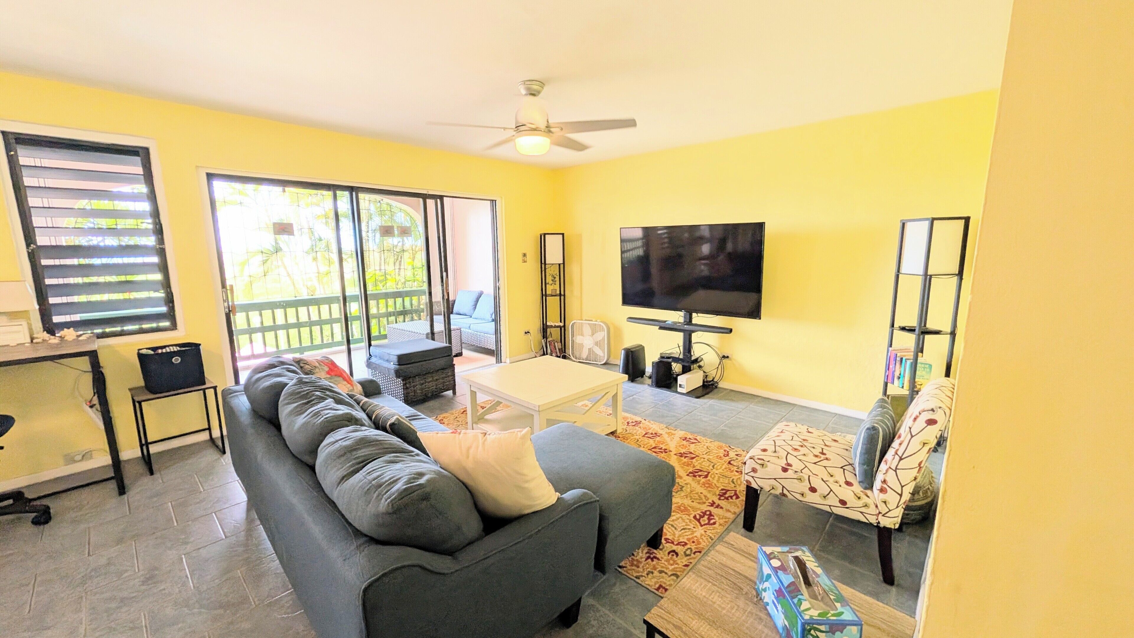 A living room with a sofa, a coffee table, a TV, and a ceiling fan.