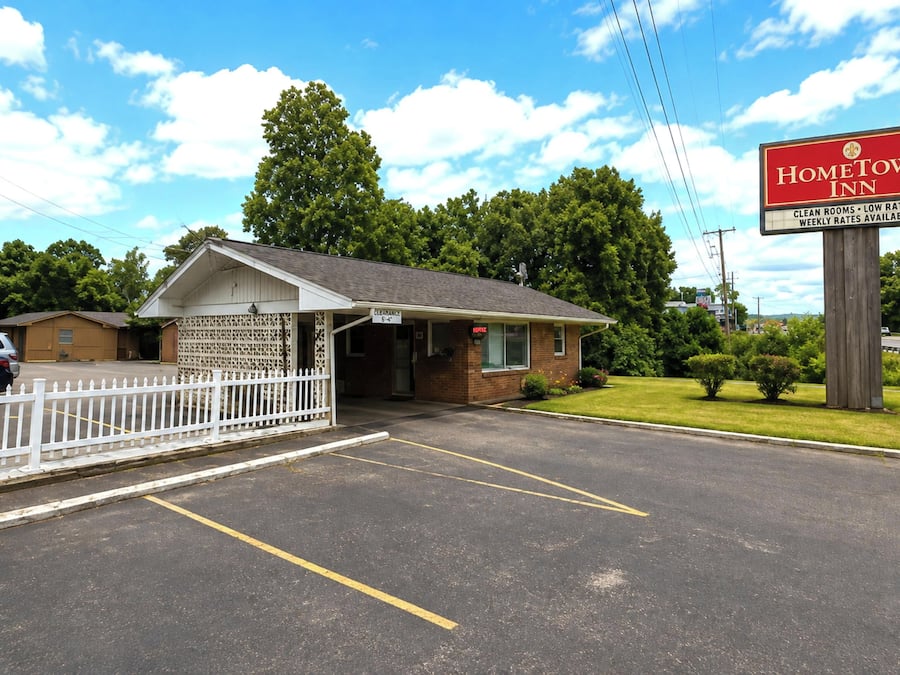 Ein Motel mit einem Schild, das 'HomeTown Inn' und 'Saubere Zimmer – Niedrige Preise' bewirbt.