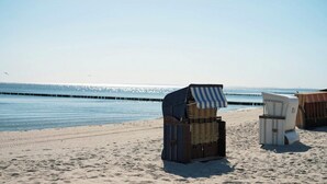 Strandstolar staplade på sanden nära vattnet.