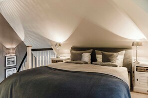 A bedroom with a bed, nightstands, and a staircase. - Luxury apartment with water view in Loddin (Kamphof)
