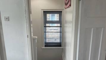 A hallway with a window, a door, and a light fixture.