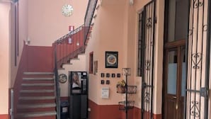 A staircase leading to an upper floor, a door with a metal gate, and a wall with framed pictures.
