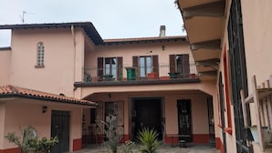 A two-story building with a balcony, potted plants, and a small outdoor seating area.