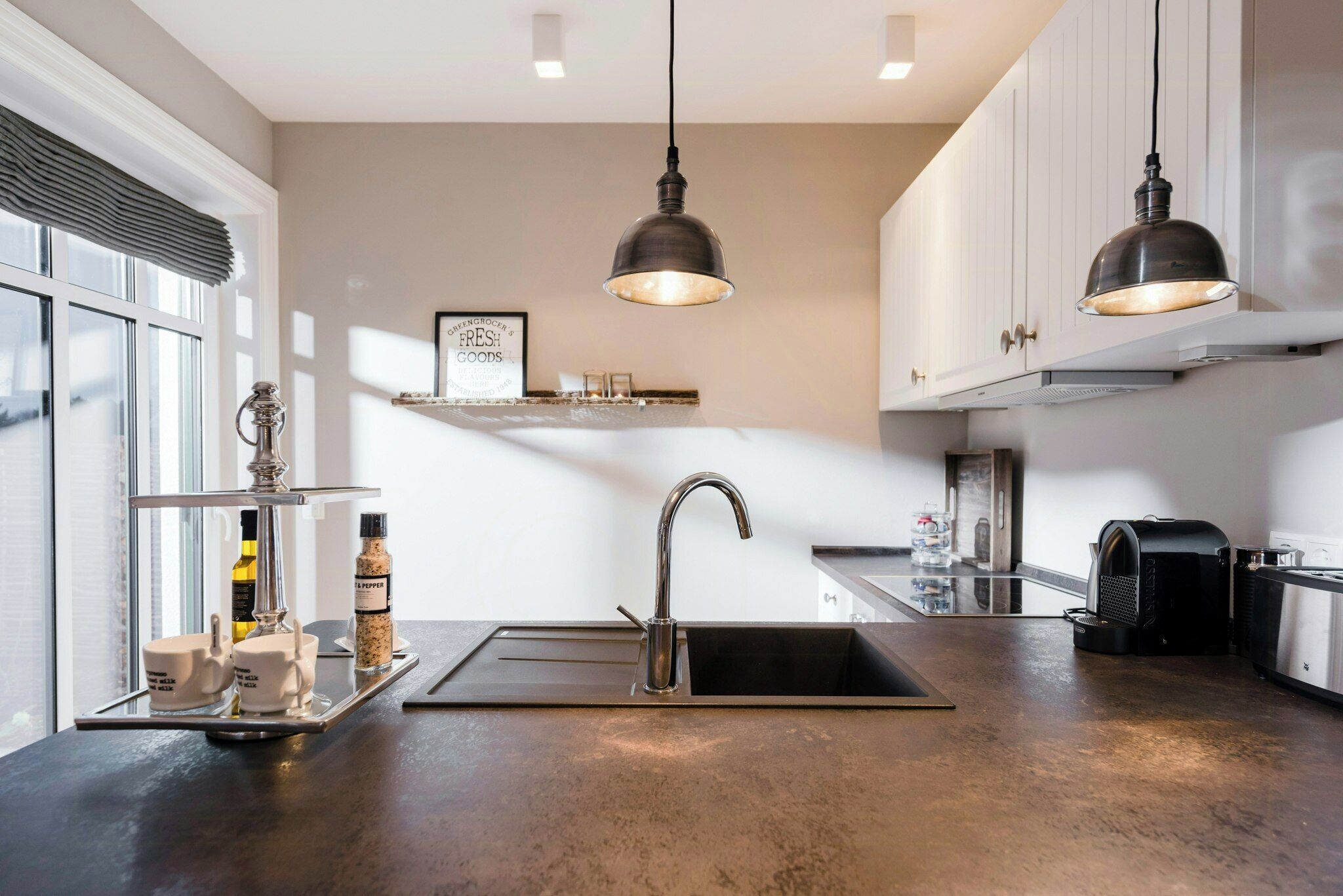Una cocina moderna con un lavamanos de acero inoxidable, luces colgantes y una cafetera.