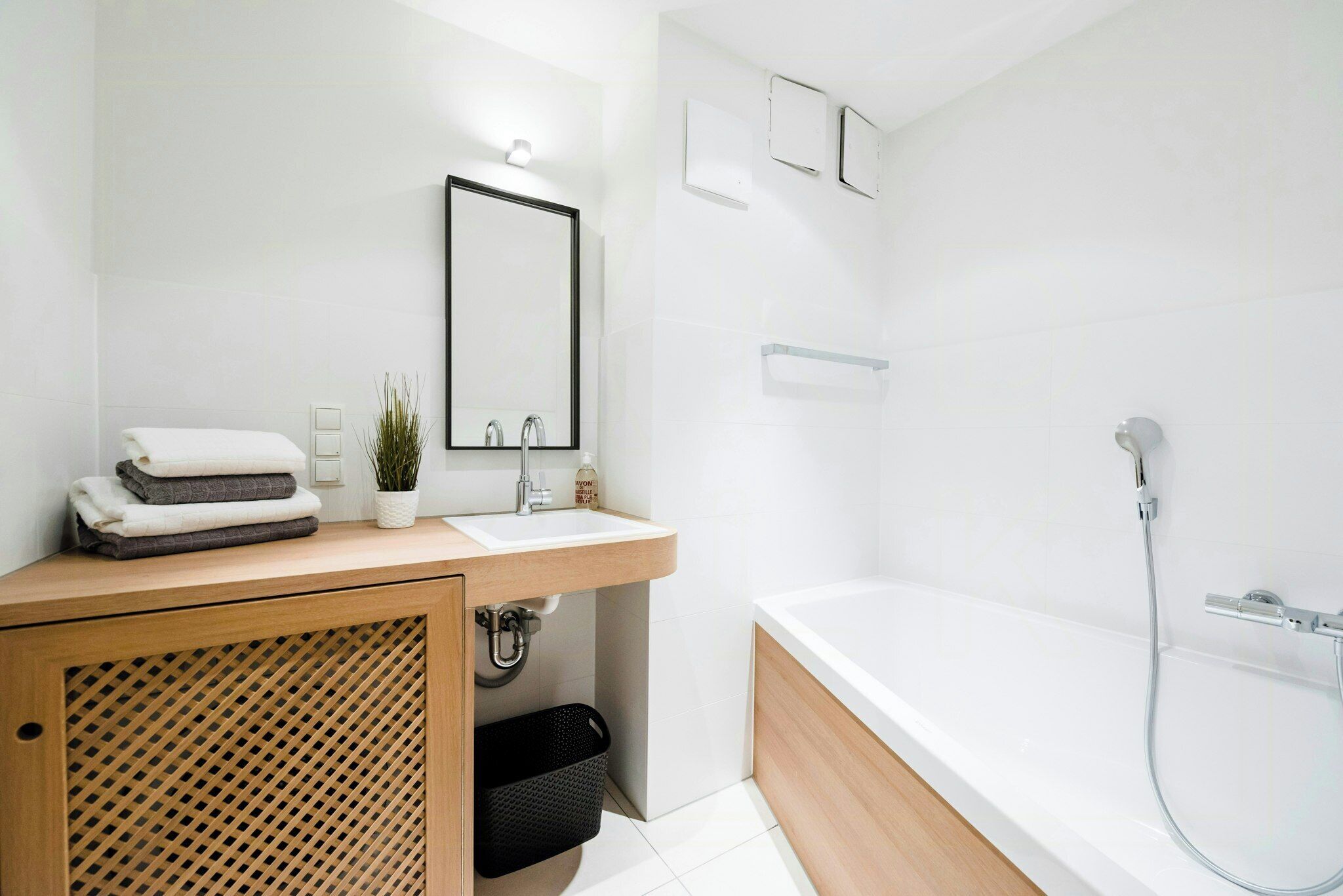 A modern bathroom with a white sink, mirror, and bathtub.