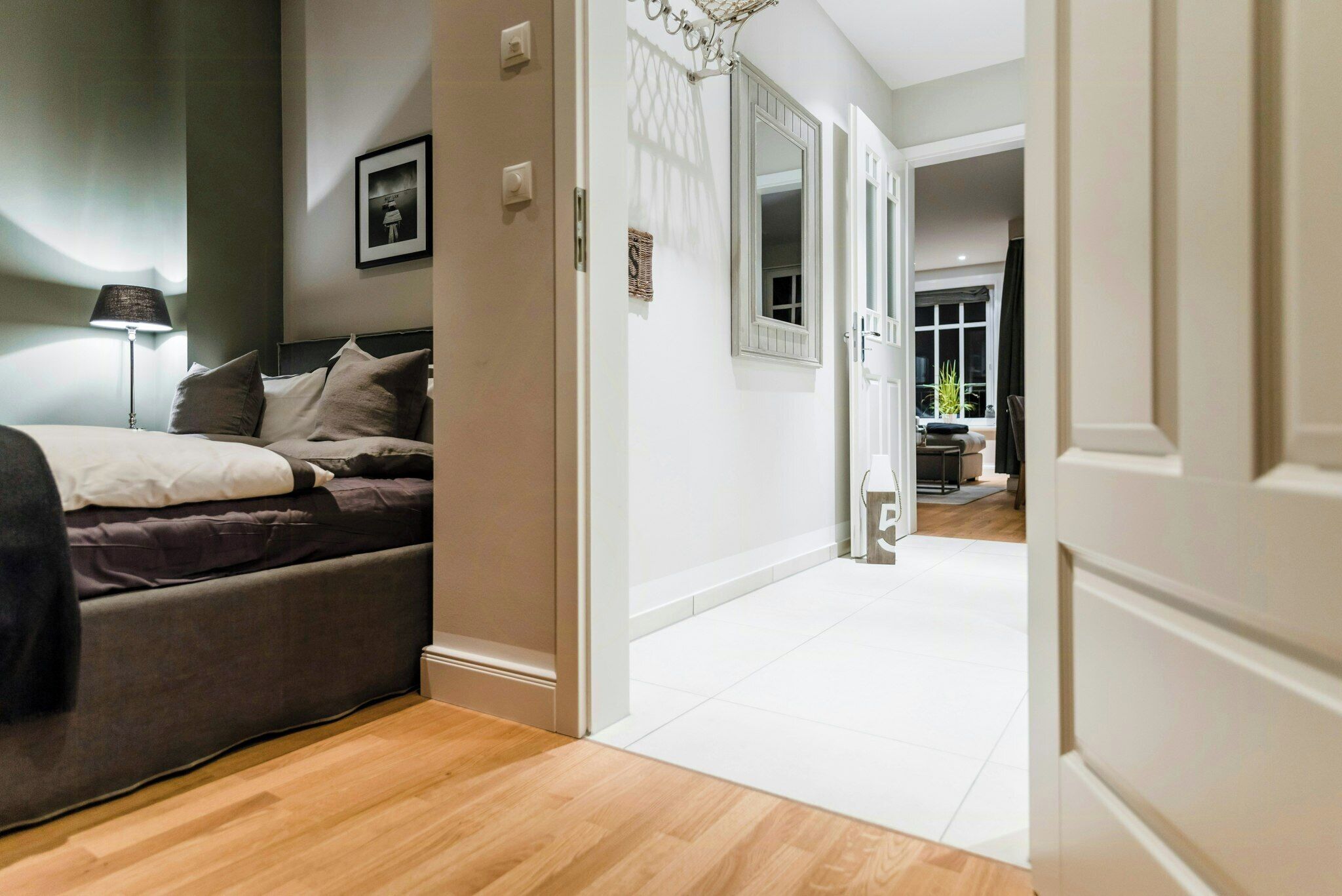 A bedroom with a bed, bedside lamp, and a door leading to a hallway.