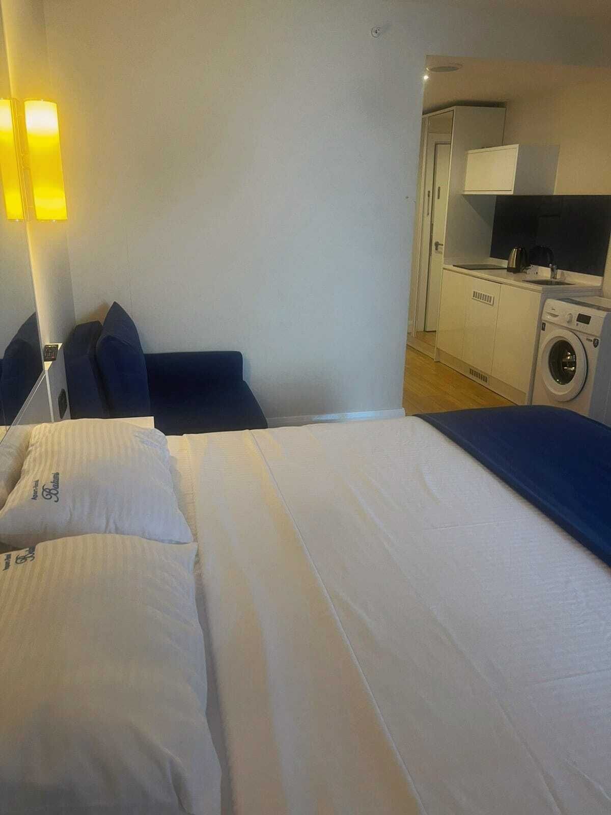 Una habitación de hotel con una cama, una kitchenette pequeña y una lavadora.