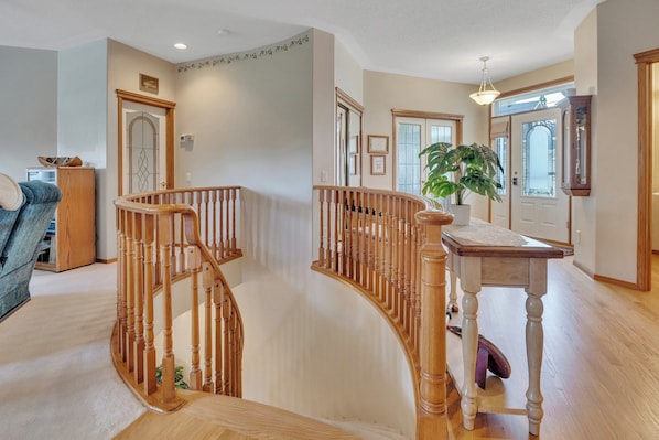 A spacious living area with a wooden staircase, a dining table, and a large window.