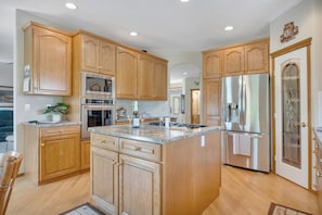 A kitchen with wooden cabinets, stainless steel appliances, and a large island.