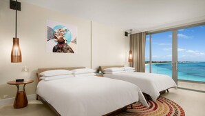 A hotel room with two beds, a large window with a view of the ocean, a painting on the wall, and a modern pendant light. - Andaz Turks And Caicos At Grace Bay (Providenciales)