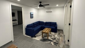 Un salon moderne avec un canapé d’angle, une table basse en bois et un ventilateur de plafond.