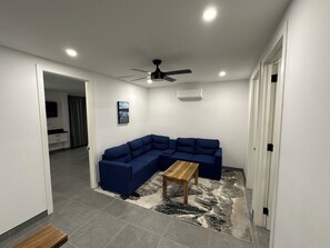 Una sala moderna con un sofá modular, una mesa de centro de madera y un ventilador de techo.