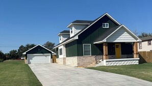 Ein Wohnhaus mit Auffahrt, Garage und Veranda.