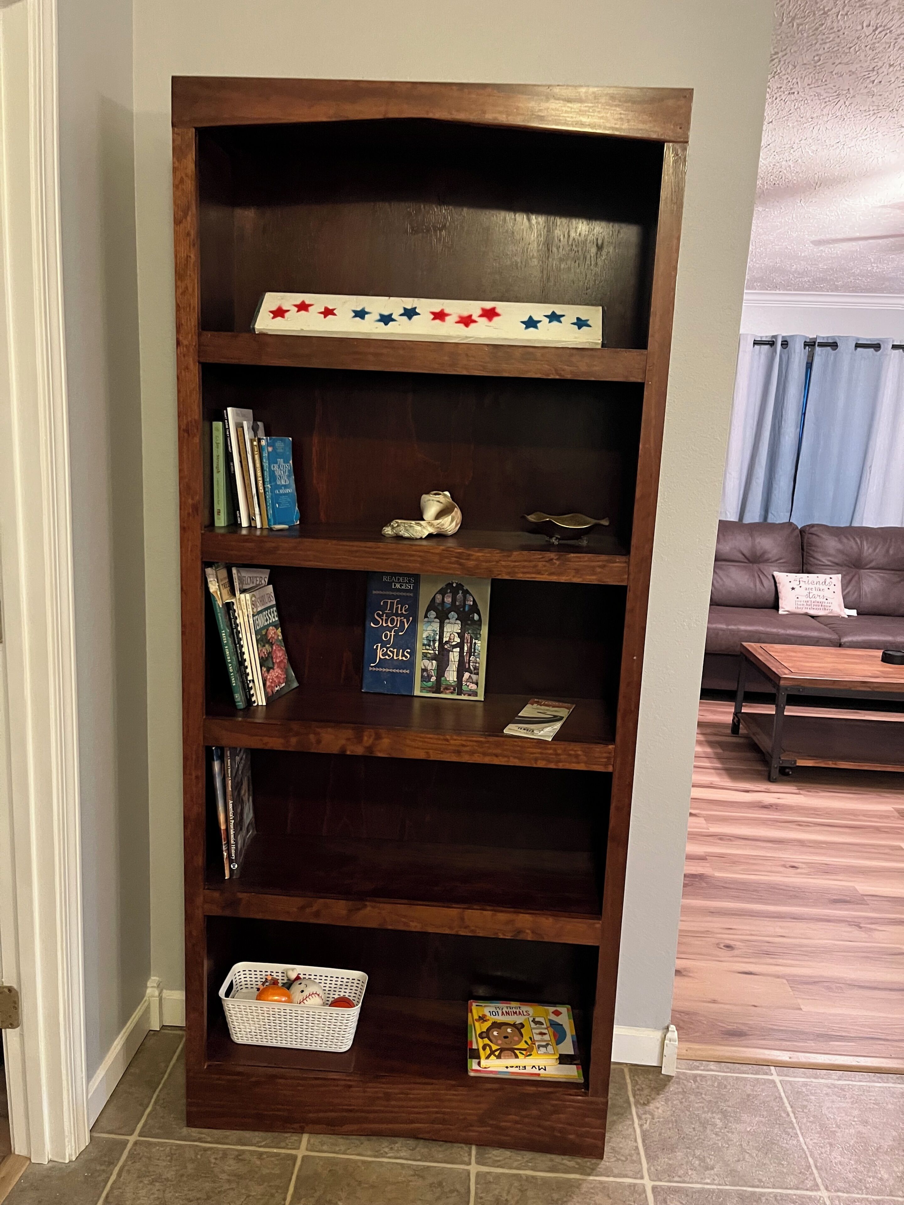 A wooden bookshelf with books, a decorative item, and a basket with oranges.