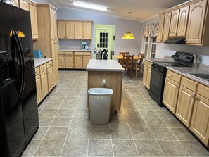 A kitchen with wooden cabinets, a black refrigerator, a dishwasher, and a tiled floor. - Overlook Nook, 3-bedroom house in charming Kodak (Kodak)