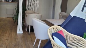 Un intérieur moderne comprenant un coin repas, un fauteuil en osier et une structure évoquant une tente.