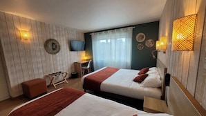 Une chambre d’hôtel avec deux lits, un bureau, une chaise, une télévision et des appliques murales décoratives.