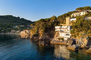 Ein Küstenhaus mit mehreren Balkonen, gelegen auf einem felsigen Felsen mit Blick auf das Meer.
