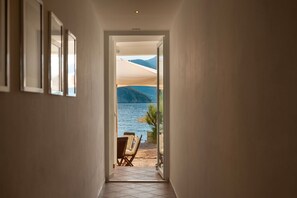 Corredor que dá para uma varanda com vista para um lago e montanhas.
