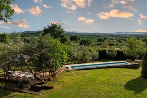 A swimming pool surrounded by a grassy lawn, trees, and a stone wall. - Villa Il Ritiro 8, Emma Villas (Villa San Giovanni in Tuscia)