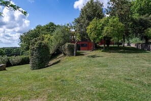 A grassy area with trees and a building with a red facade. - Villa Il Ritiro 8, Emma Villas (Villa San Giovanni in Tuscia)