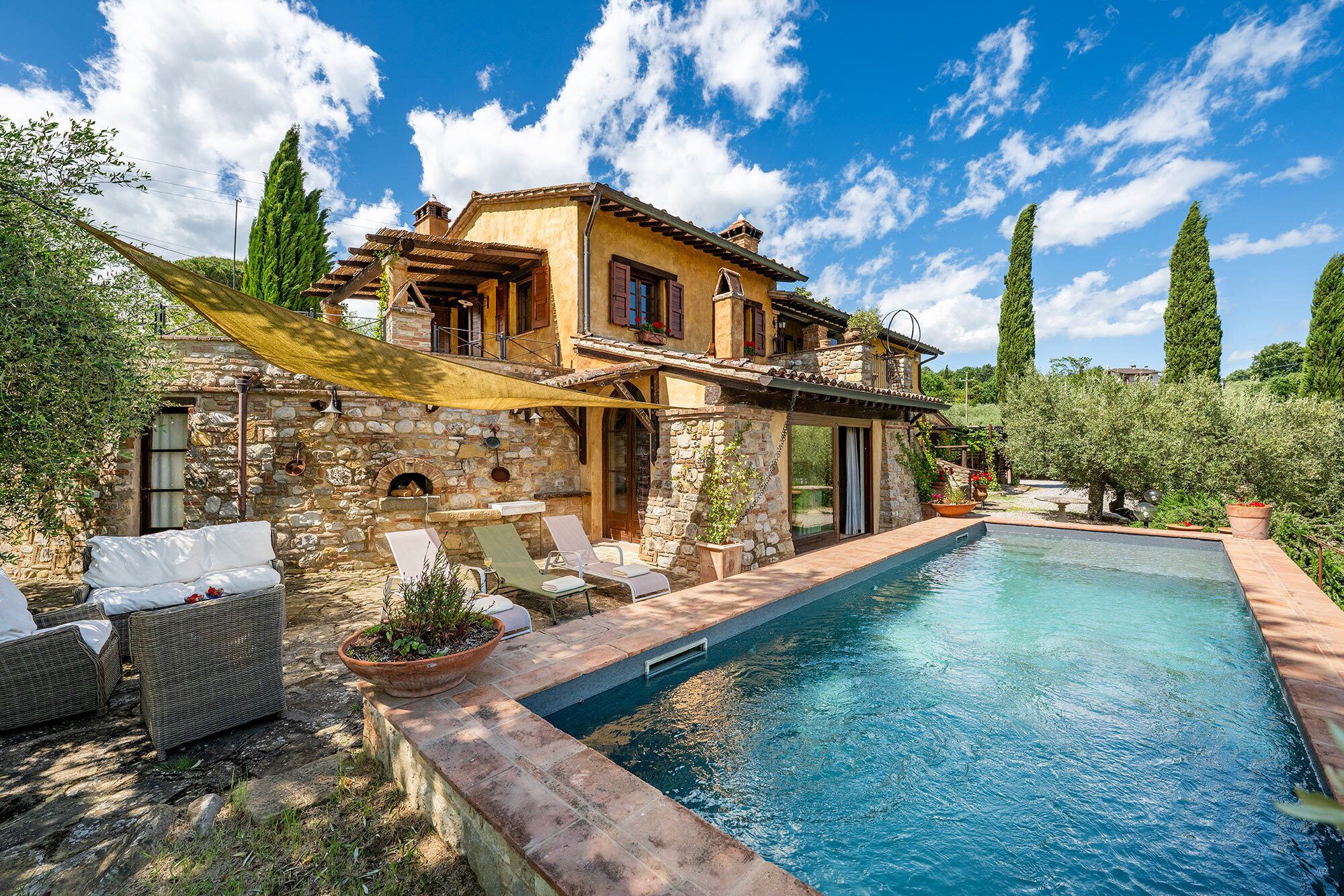 A villa with a swimming pool, stone walls, and outdoor seating.