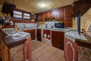 A kitchen with wooden cabinets, a tiled backsplash, a built-in oven, and a countertop with various kitchen items.