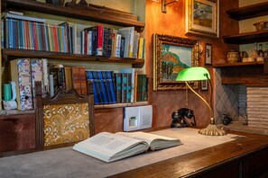 A study area with bookshelves, a desk, a lamp, and a vintage telephone. - Colle Calzolaro 8, Emma Villas (Tavernelle)