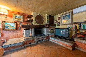 A cozy living room with a fireplace, television, and various framed artworks. - Colle Calzolaro 8, Emma Villas (Tavernelle)