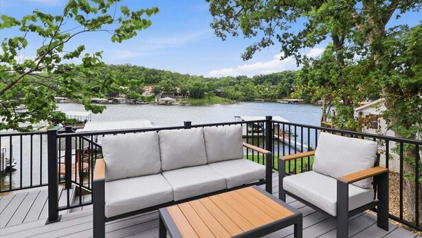 A deck with a sofa and chairs, overlooking a lake with boats and houses in the background. - Private Dock, Boat & PWC Slips, Fire Pit, Lake Views (Rocky Mount)