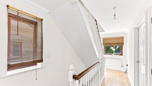 Una escalera con barandillas blancas y peldaños de madera que conduce a una plataforma con ventanal.