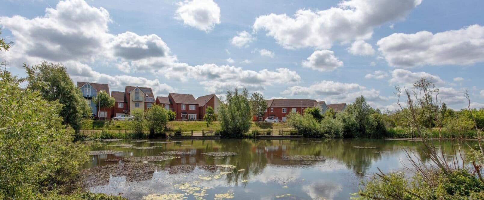 Un quartier résidentiel avec des maisons, un étang et un ciel dégagé.
