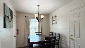 A dining room with a wooden table and chairs, a chandelier, and a door with a decorative panel.