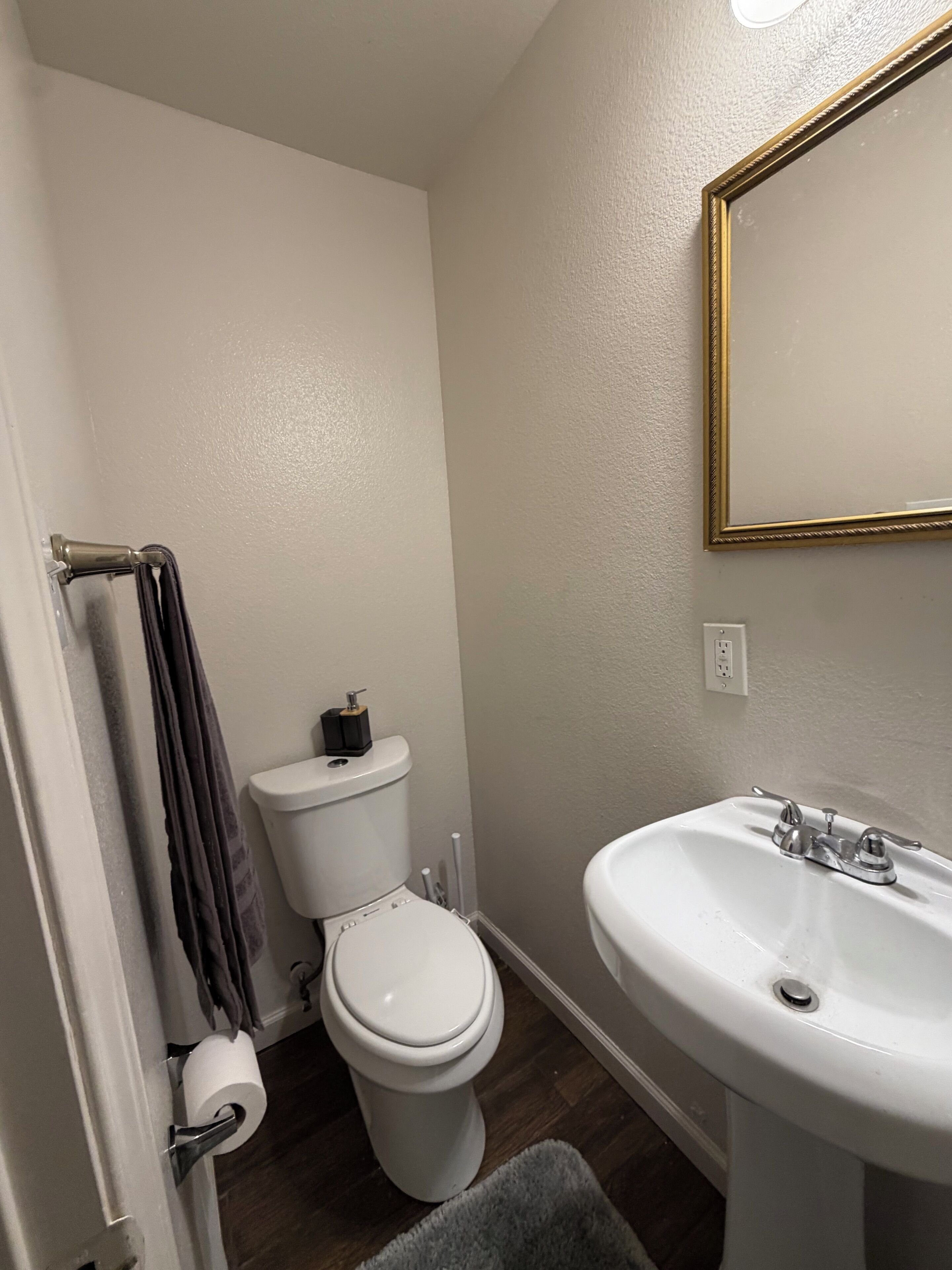 Een badkamer met toilet, wastafel en spiegel.