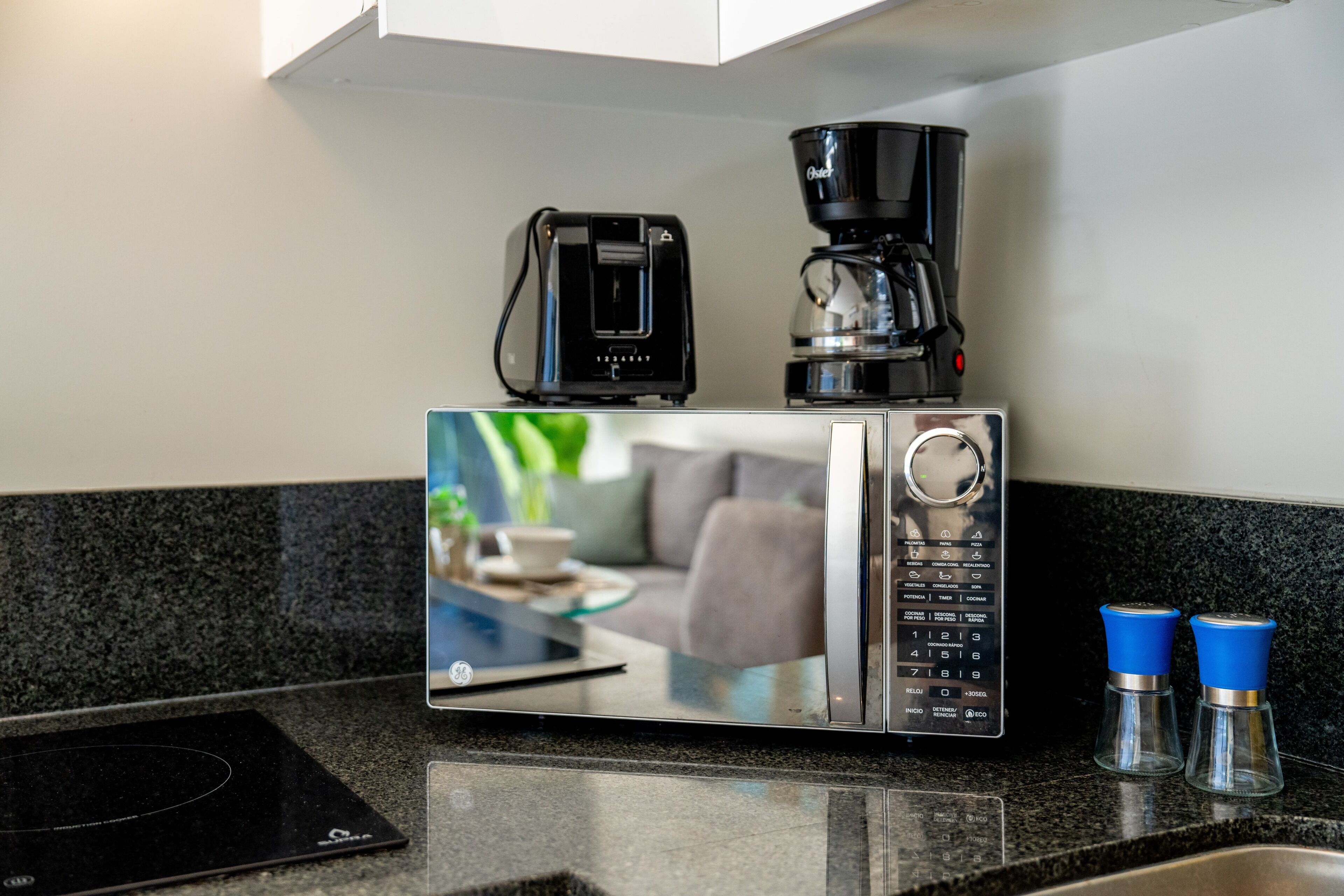 Una cocina con cafetera, microondas y dos saleros y pimenteros en la encimera.