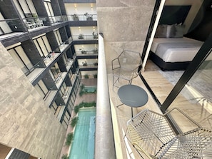 A high-rise building with multiple balconies, a swimming pool, and a bedroom with a bed and a chair. - Musa del Carmen (México)