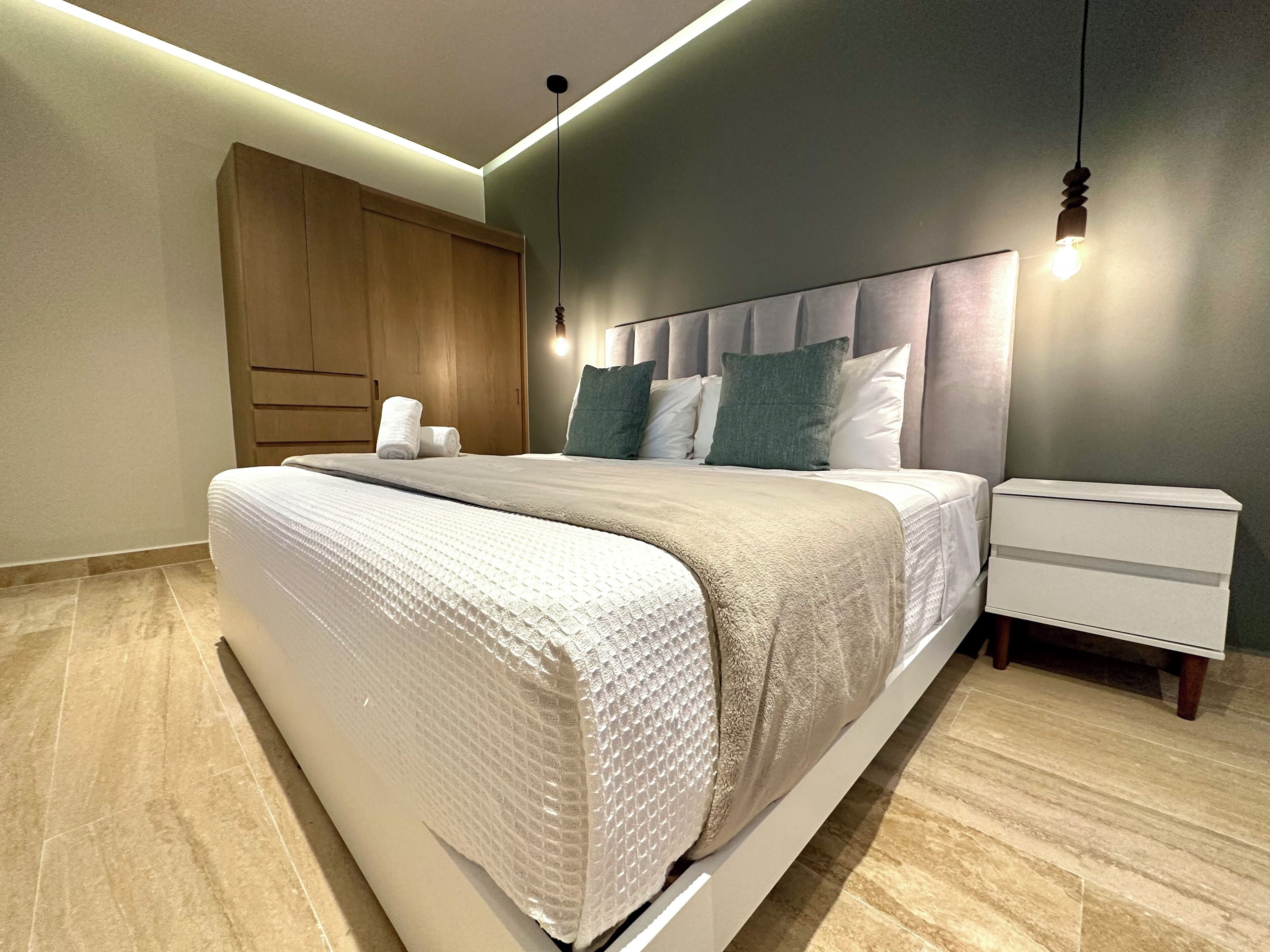 A modern bedroom with a bed, bedside tables, and a wardrobe.
