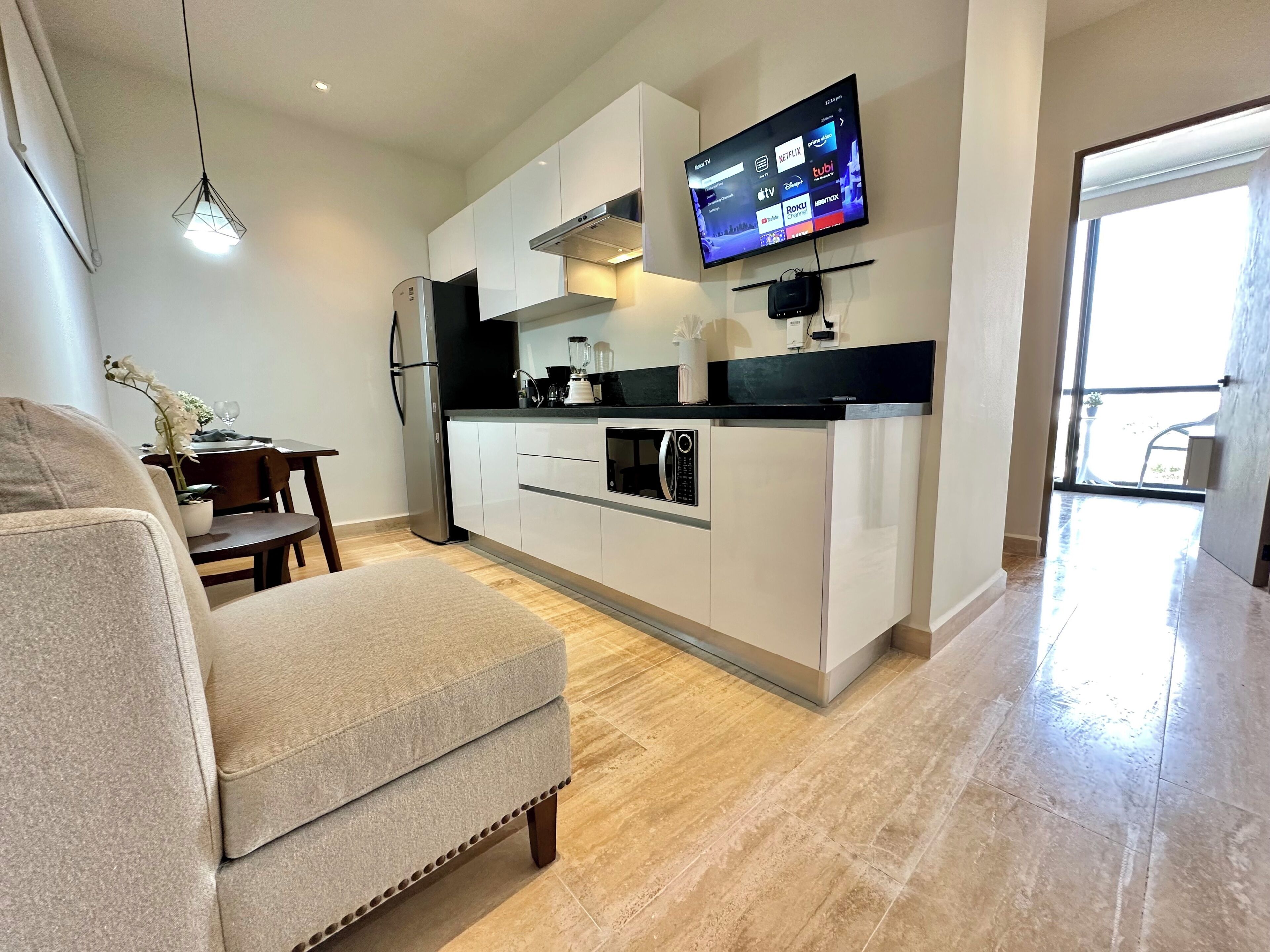 Eine moderne Küche mit Flachbildfernseher, ein Essbereich mit Tisch und Stühlen sowie eine Sitzecke mit Sofa.
