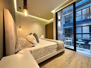 A modern bedroom with a bed, bedside table, and a view of the outside. - Musa del Carmen (México)