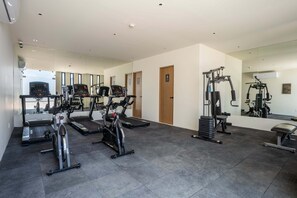 Un gimnasio con máquinas de cardio, equipo de levantamiento de pesas y un espejo grande.