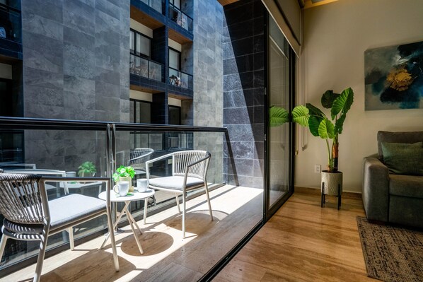 Un interior moderno con balcón, zona de estar y planta en maceta.