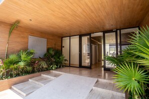 Un edificio moderno con techo de madera, puertas de cristal amplias y plantas de interior.
