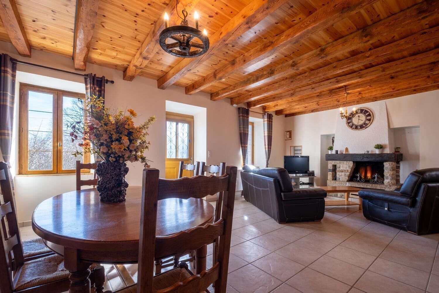 Un intérieur en bois comprenant une table à manger, des chaises, un canapé, une cheminée et un téléviseur.